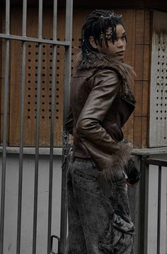 a man with dreadlocks standing next to a fence