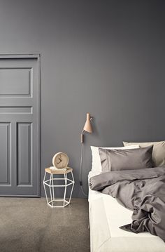 a bedroom with gray walls and white bedding, an open door to another room