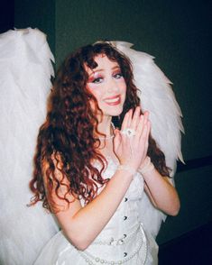 a woman dressed as an angel holding her hands together