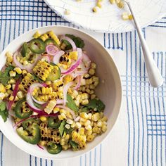 a white bowl filled with corn, onions and green peppers on top of a blue and white table cloth