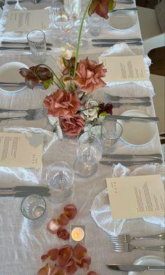 the table is set with silverware, flowers and menus for an elegant dinner