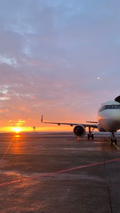 an airplane sitting on the tarmac at sunset