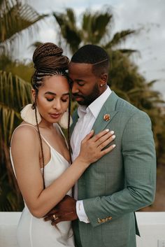 a man and woman embracing each other with palm trees in the background