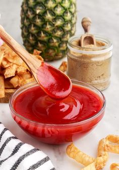 a person holding a wooden spoon over a bowl filled with ketchup and chips