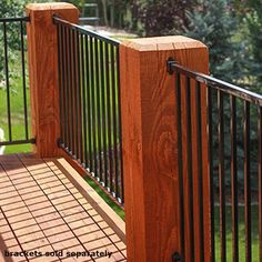 a wooden deck with metal railings and trees in the background