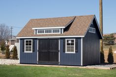 a small blue shed sitting in the middle of a field