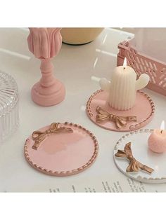 three pink plates with candles on them sitting on a white table next to a candle holder