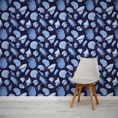 a white chair sitting in front of a wall with blue and white designs on it