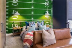 a bedroom with a football themed wallpaper and leather couch in front of the bed