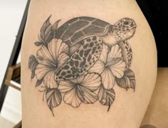 a turtle and flowers tattoo on the thigh