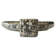 an antique style diamond ring with two diamonds on the band and a center stone in the middle