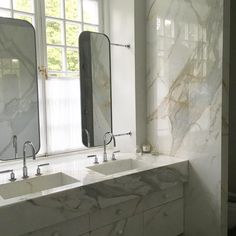 two sinks and mirrors in a bathroom with marble counter tops on either side of them