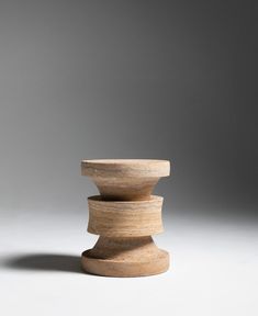 three stacked wooden objects sitting on top of each other in front of a gray background