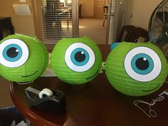 two green paper balls with blue eyes on them sitting on a table in front of a fan