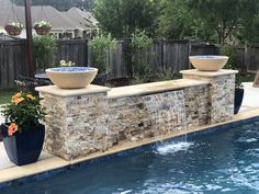 an outdoor swimming pool with two large bowls on the wall and water running down it