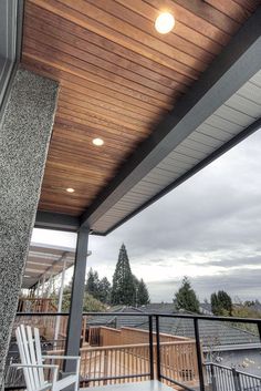 an outdoor deck with chairs and lights on the ceiling is shown in this image, looking out over the city