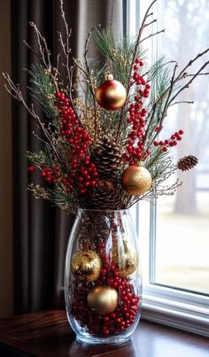 a vase filled with christmas decorations on top of a wooden table next to a window