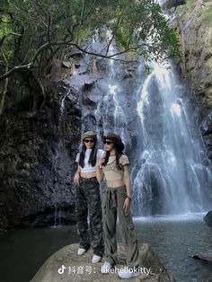 two women standing in front of a waterfall