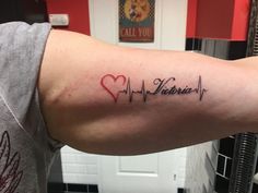 a person with a heart and heartbeat tattoo on their arm