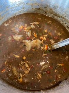 a pot full of soup with a spoon sticking out of the top and meat in it