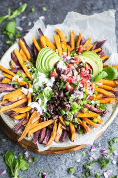 a plate filled with french fries, avocado and other toppings on top of it