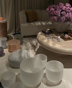 there are many bowls and cups on the table in front of a couch with flowers