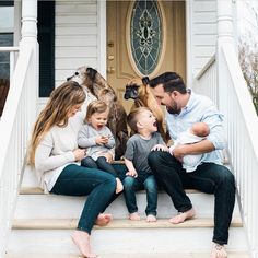 a family sitting on the front steps of their home