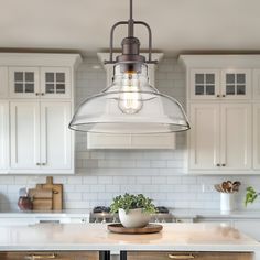 a kitchen with white cabinets and an island in front of the countertop, has a glass dome light fixture hanging over it