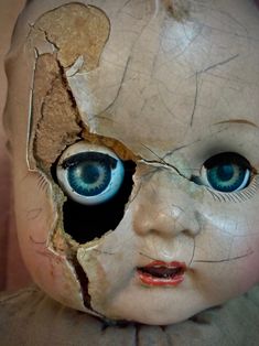 an old doll with blue eyes is shown in this close up photo, it appears to have been torn apart