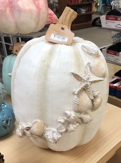 a white pumpkin decorated with seashells and starfish is on display in a store