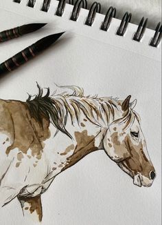 a drawing of a brown and white horse next to two black markers on a piece of paper