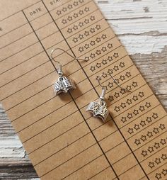 two silver earrings sitting on top of a piece of paper