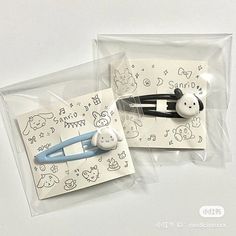 two pieces of plastic with cartoon drawings on them, one has a hair clip and the other has a pen in it