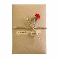 a brown envelope with a red rose tied to it