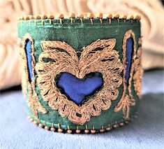 Regal blue hearts are framed with gold metal embroidery on green silk and edged with glass seed beads.  This lovely cuff bracelet is made from reclaimed vintage sari trim. Cuff measures approximately 7 x  inches with a 2 inch extender, fitting up to a 9 inch wrist. Hardware is antique bronze metal with a lobster clasp closure.  Sari trim has been gently cleaned, stabilized with a cotton interfacing and backed with new blue felt.  *Please note that upcycled materials may show signs of wear.* Custom Bachelorette Shirts, Metal Embroidery, Fabric Bracelets, Blue Hearts, Vintage Sari, Textile Jewelry, Vintage Saris, Reclaimed Vintage, Bronze Metal