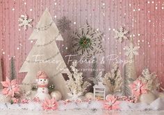 a christmas scene with snowmen, trees and other decorations on a table in front of a pink wall