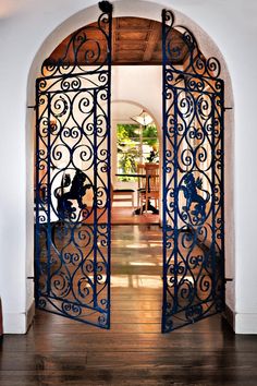 an ornate iron gate is open to the living room and dining area, which also has wood flooring