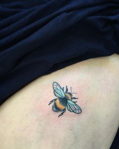 a small bee tattoo on the back of a woman's stomach