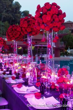 a long table is set with red roses and candles for an elegant dinner or party