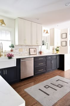 a kitchen with black and white cabinets, wood floors and a rug on the floor