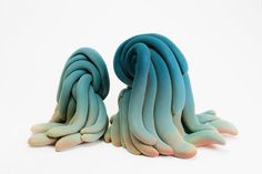 two pieces of blue and green art made out of clay sitting on top of each other