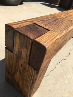 a wooden bench sitting on the side of a road next to a parked truck and another vehicle