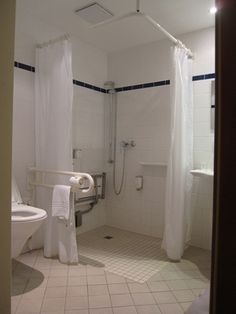 a bathroom with a shower, toilet and sink in it's stall door open