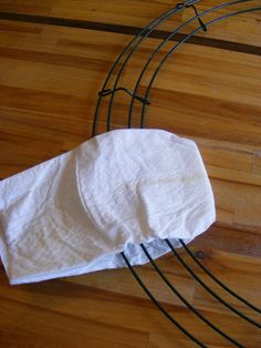 a white towel sitting on top of a wooden floor next to a black wire rack