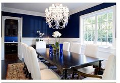 a dining room table with white chairs and a chandelier