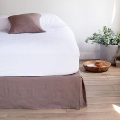 a bed sitting on top of a wooden floor next to a potted plant