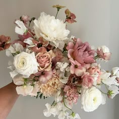 a person holding a bouquet of flowers in their hand with the background white and pink