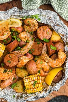 shrimp, potatoes and corn on the cob in foil with parsley garnish