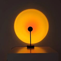 a lamp that is sitting on top of a white surface with a yellow light behind it