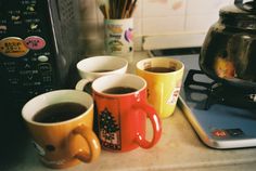 three coffee mugs sitting on top of a counter next to a toaster oven